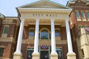 the front of a city hall with columns and a flag