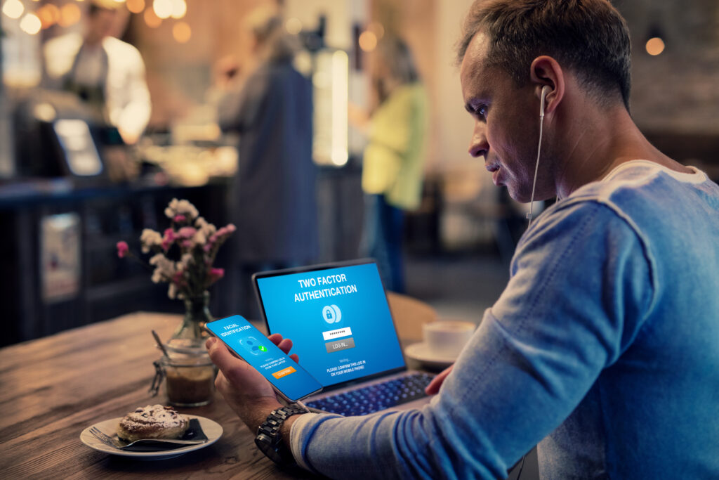 Man using two factor authentication on laptop computer and mobile phone